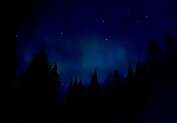 Ribbons of green and purple aurora stretched across a star-filled night sky.