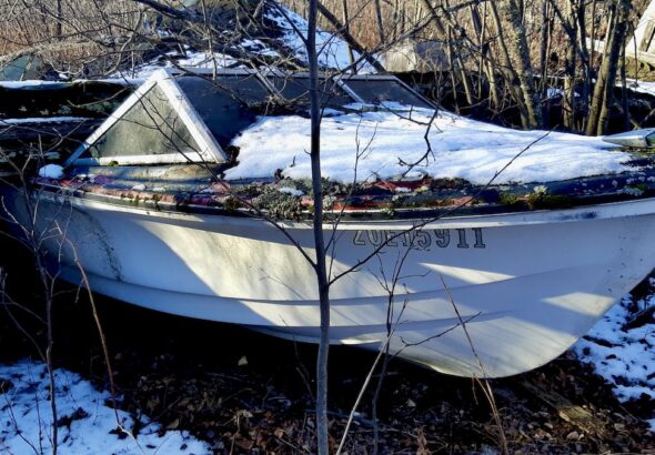 An abandoned boat rests beneath the remains of a fallen garage in Borups Corners. Once a vessel of open water, it now holds the stillness of forgotten years.