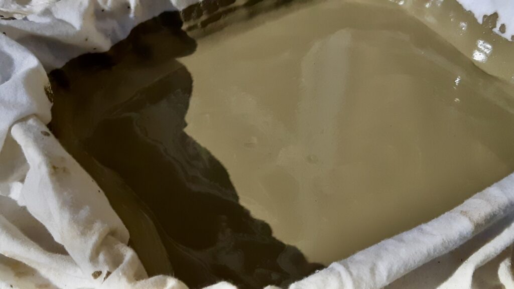 The t-shirt acts as a built-in release liner and a clever material handler. As the clay dries and loses its stickiness, you can simply grab the corners of the shirt to lift the entire mass cleanly out of the pan, giving you a tidy bundle that can be wedged right on the fabric or left to dry completely so it can be pulverized for future storage.