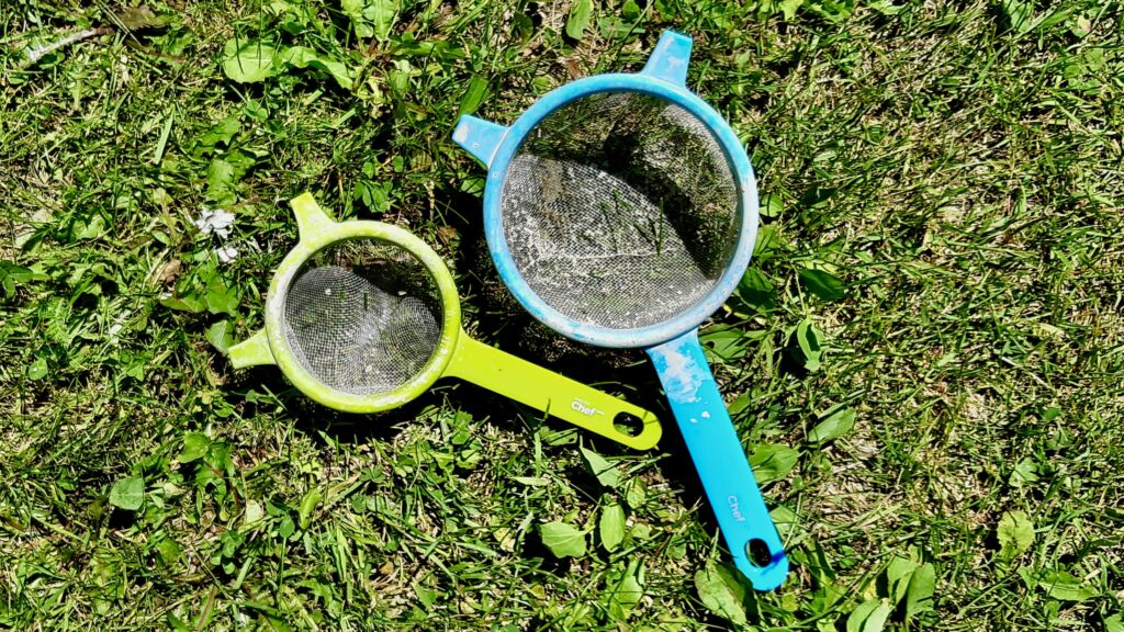 Everyday wire-mesh kitchen strainers do the exact same job as expensive industrial pottery sieves. They can be vigorously tapped and rinsed clean with a garden hose between batches, making them one of the ultimate zero-cost refining tools.