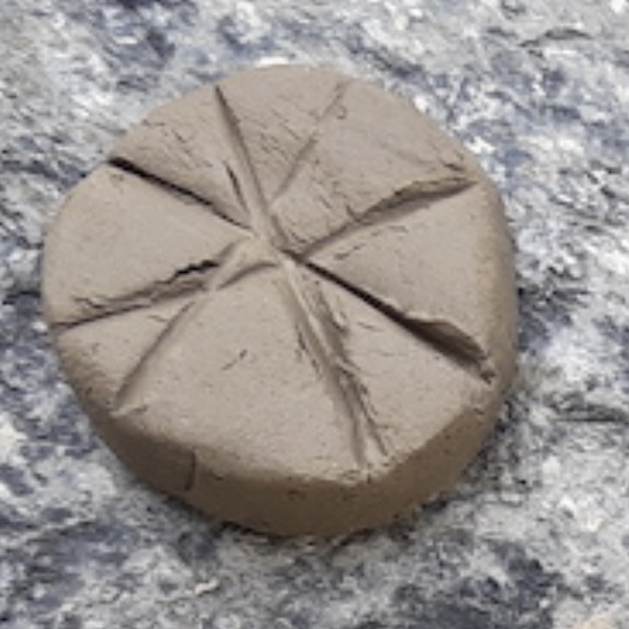 Before: The wet wild clay puck with straight intersecting lines pressed into the top surface, set out to air-dry on a granite boulder.