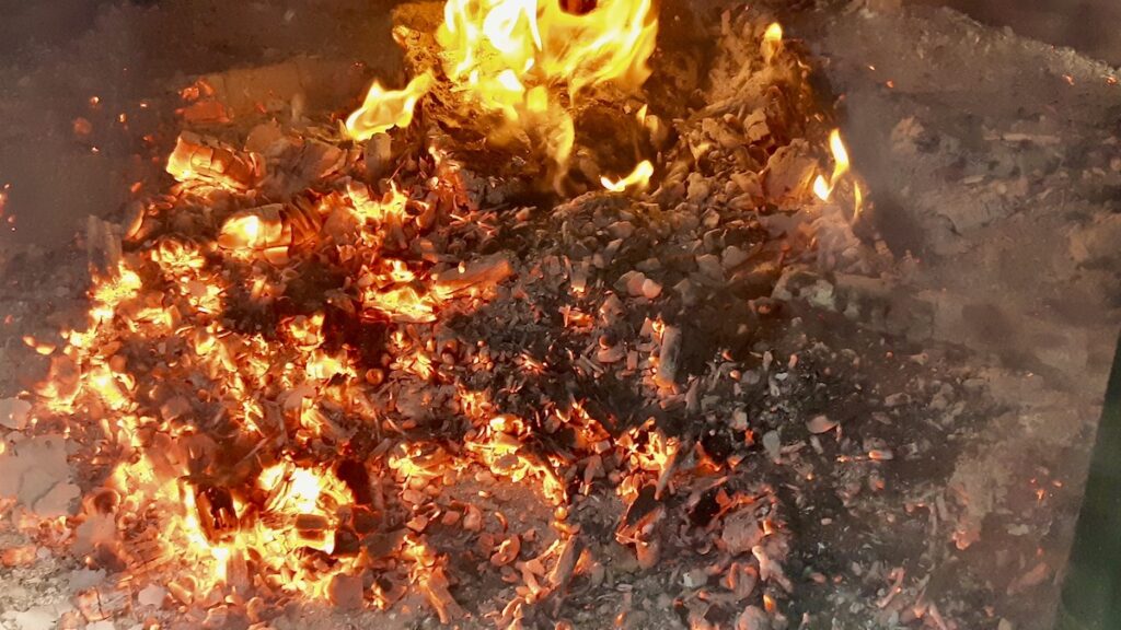The flames have been burning for hours, and there's a deep layer of glowing coals over our clay pieces. Our first pit firing is a big milestone in the ongoing clays and ceramics experiments we've been working on in Melgund Township. Once everything has cooled completely, we'll be able to uncover the pieces and see what happened beneath all that heat and ash.