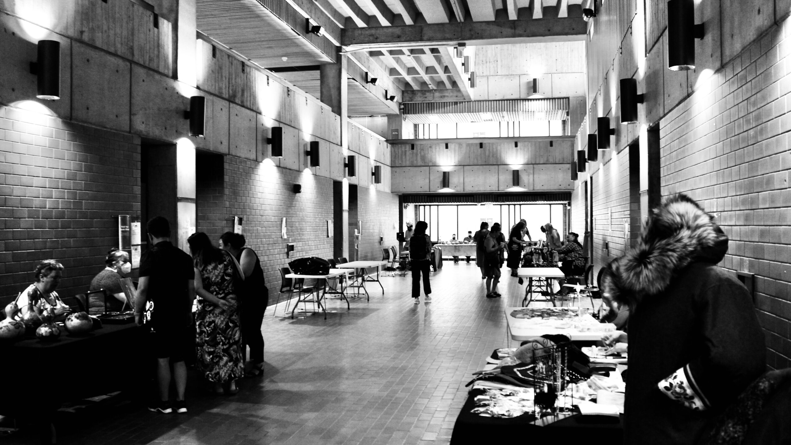 Inside a corridor built for function, time folds. Artists unfurl memory onto tables, turning concrete into ceremony. The space hums—not with commerce, but with return. Every glance, a stitch. Every exchange, a quiet reclamation. What was paused begins again, not as before, but more deeply rooted.