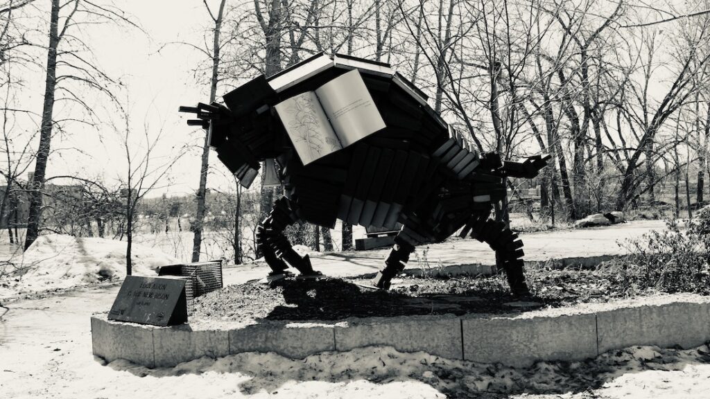 Among bare branches and snow-laced silence, the book-buffalo waits—pages frozen in time, wisdom stacked into muscle and memory. It is not sculpture, but spellwork. It holds what we forgot we carried: story, survival, and the soft hoofbeats of future paths.
