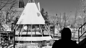 In Winnipeg’s playgrounds, metal tipis rise like echoes of old songs, catching sky in their spines. These are not structures but spells—frames for imagined fires and stories unspoken. Here, laughter roots in the dust, spiraling upward. Memory plays barefoot, circling the sacred geometry where past and future quietly braid. Photo: Jamie Bell