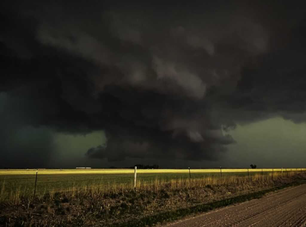 In this eery shot, a LRWC (lowered rotating wall cloud) produced intense downburst winds 5 miles east of Larned, Kansas. As this system moved into warmer air, it produced multiple funnels and intense dust vortices. Photo by Ethan Caners.