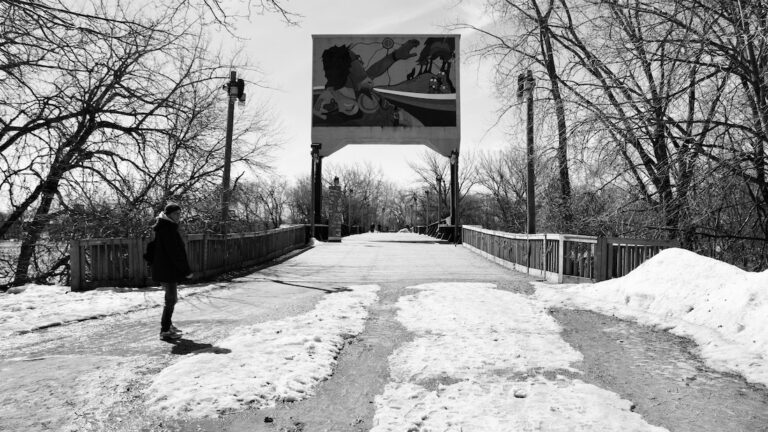 Beneath the rusted lattice of the old rail bridges near the Forks, time bends—steel bones whispering histories into the wind, footsteps echoing between memory and motion. The river moves slow and thick below, like thought unspoken, while overhead the iron arches cradle sky and silence.