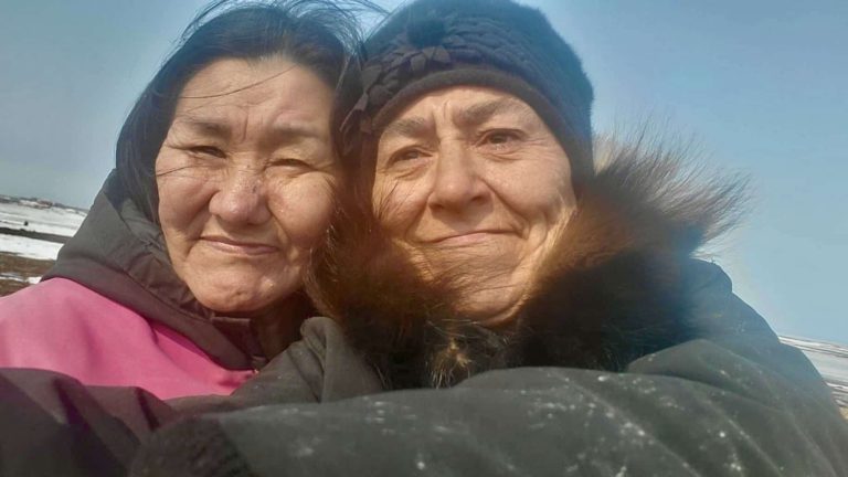 Cultural advisors Lucy Eetak (left) and Eva Suluk (right) enjoy a day of drying meat and reconnecting with the land that grounds their knowledge and care, near Arviat, Nunavut. Their collaborative spirit and visible joy highlight the importance of their role in passing on traditional skills and cultural wisdom.
