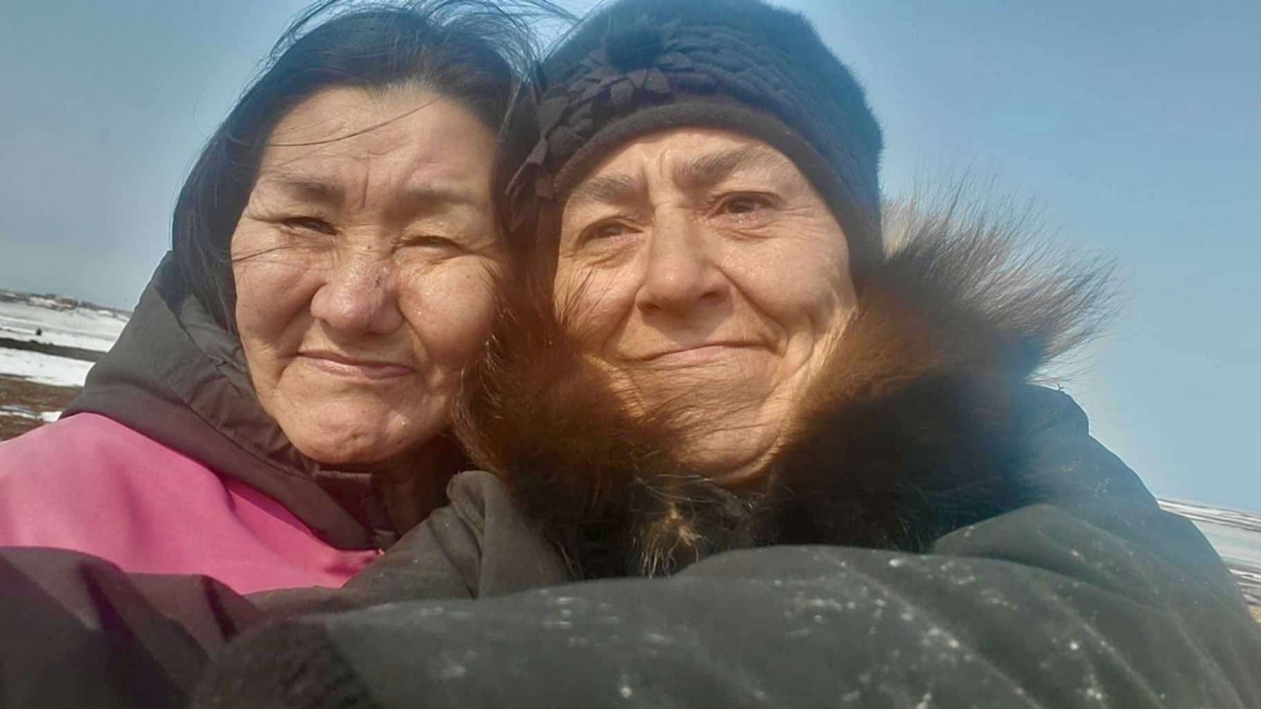 Cultural advisors Lucy Eetak (left) and Eva Suluk (right) enjoy a day of drying meat and reconnecting with the land that grounds their knowledge and care, near Arviat, Nunavut. Their collaborative spirit and visible joy highlight the importance of their role in passing on traditional skills and cultural wisdom.