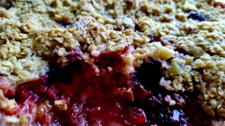 Dive into the irresistible texture of our homemade Strawberry Rhubarb Crisp! This close-up reveals the bubbling, vibrant fruit filling bursting with sweet and tart flavors from fresh garden strawberries and rhubarb, perfectly complemented by the golden-brown, buttery oat crumble topping. Every spoonful promises a delightful balance of juicy fruit and crunchy goodness, making it the ultimate comfort dessert for any season. Get the full recipe to bake this delicious crisp in your own kitchen!