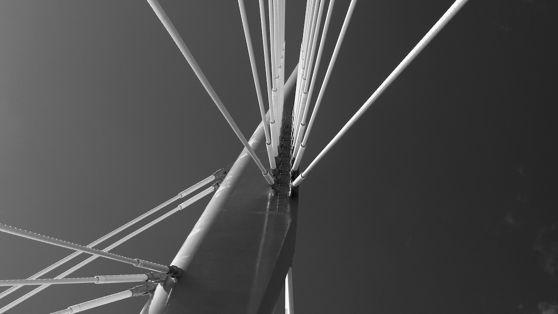 Provencher Bridge floats between breath and concrete, a tethered gesture over water’s slow murmur. Light fractures across its spine like memory refracted—half civic promise, half spectral hush. It does not span space, but thought—an architecture of pause, where crossings blur into echoes and the river forgets which way is forward. Photo: Tony Eetak