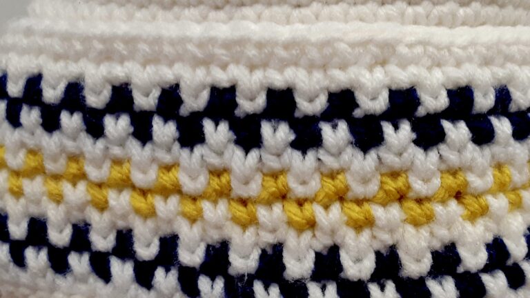 A close-up shot revealing the beautiful texture and vibrant color work in one of Lucy Eetak's meticulously crocheted hats. Each stitch tells a story of skill and passion!