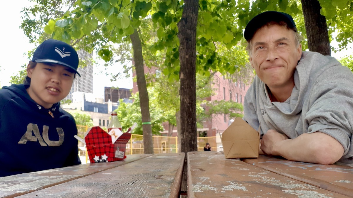 Tony Eetak and Jamie Bell, two artists from the Arts Incubator who enjoy meeting in unusual places, are talking about art from a picnic table in the Exchange District.