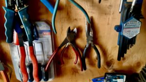 Side cutters and pliers hang ready on the plywood wall of the workshop.