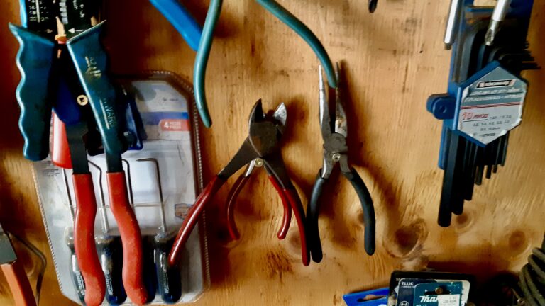 Side cutters and pliers hang ready on the plywood wall of the workshop.
