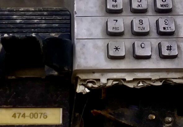 A battered and broken payphone keypad in downtown Winnipeg stands as a raw, gritty piece of accidental street art, capturing the textured history of old public communication.