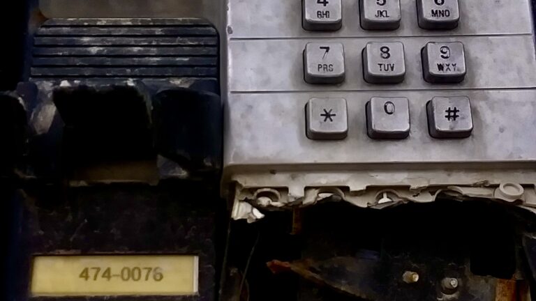 A battered and broken payphone keypad in downtown Winnipeg stands as a raw, gritty piece of accidental street art, capturing the textured history of old public communication.