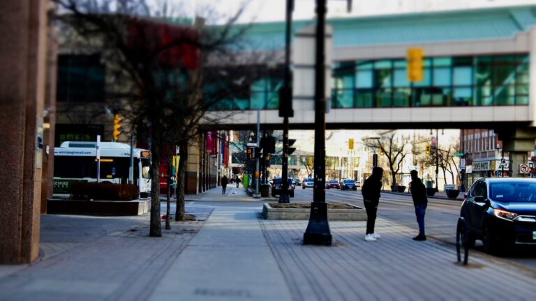 The tilt shift lens brings focus to the heart of the sidewalk, blurring the heavy traffic and overhead skywalks to emphasize the people who make Winnipeg feel truly, deeply alive.