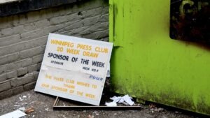 Tipped carelessly against a brick wall by a downtown dumpster, a discarded Winnipeg Press Club sign serves as a sobering monument to a forgotten era of local journalism.